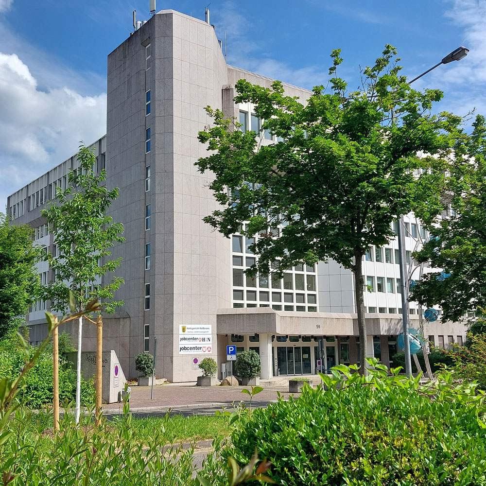 Außenansicht des Jobcenters Heilbronn, modernes Verwaltungsgebäude mit Bäumen und blauem Himmel.