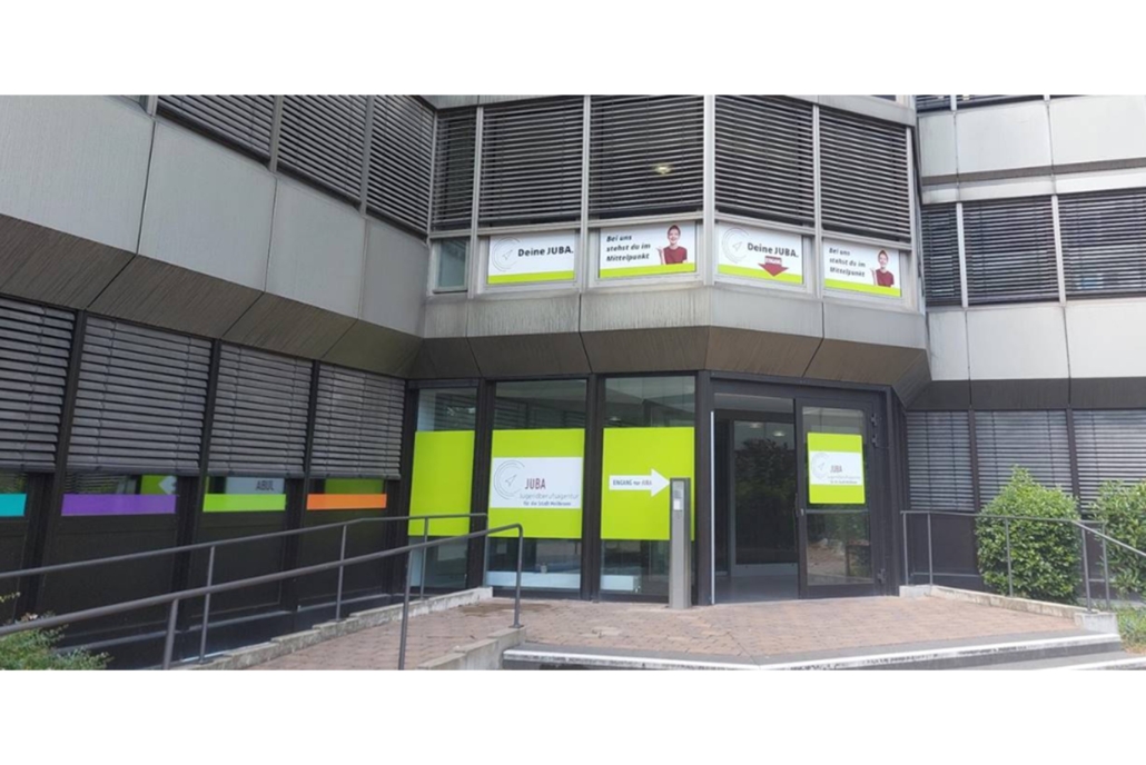 Das Bild zeigt den neuen Eingang der Juba bei der Agentur für Arbeit Heilbronn. Der Eingang ist auffällig beworben in dem leuchtenden Grün der Jugendberufsagentur.